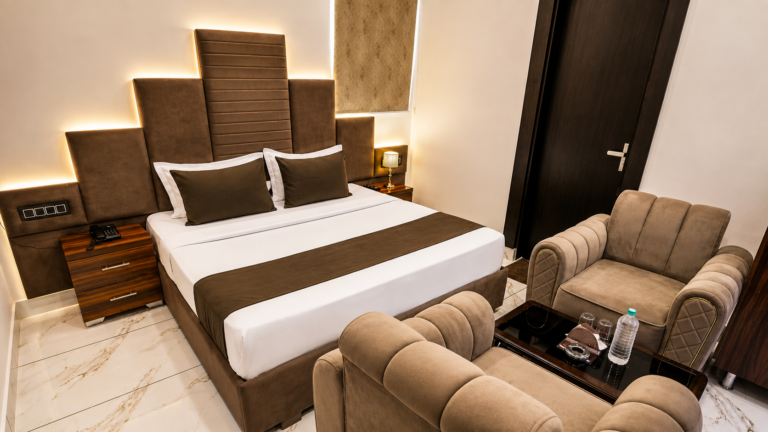 Spacious family room with a comfortable bed, sofa seating, and modern decor at Hotel Amar Raja in Kurukshetra